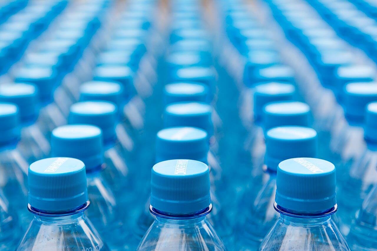 Array of blue plastic water bottles with caps arranged in a pattern. Ideal for recycling and packaging themes.