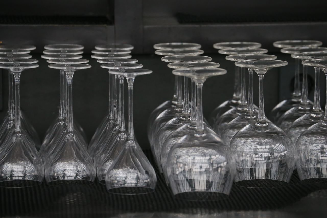 Close-up of rows of upside down wine glasses stacked in a bar setting.