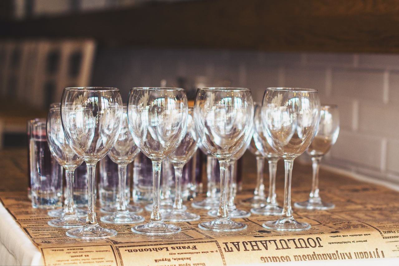 Multiple empty wine glasses arranged on a table in an elegant café setting, ready for dining or celebration.
