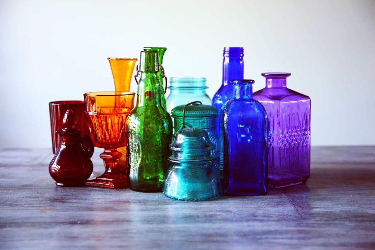 A captivating array of multicolored vintage glass bottles and containers on a wooden table.
