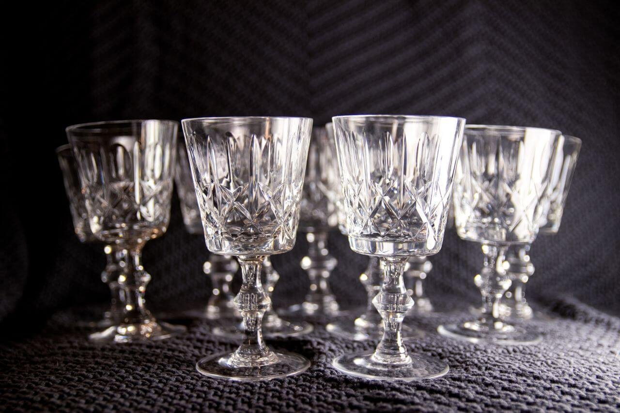 A set of elegant crystal goblets displayed on a textured fabric background under soft lighting.