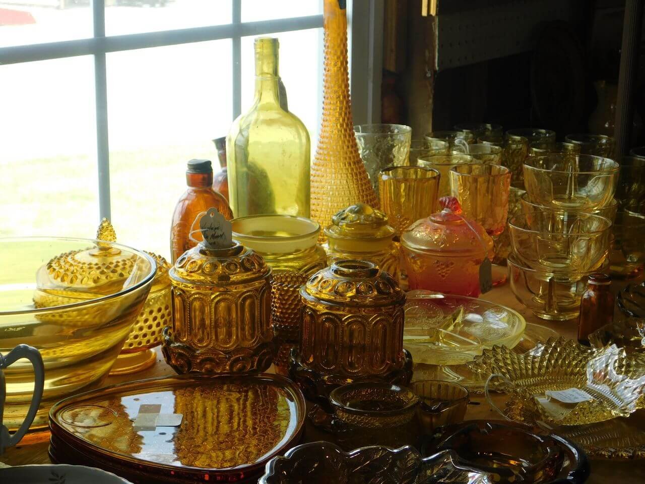 Assorted vintage amber glassware arranged by a window, creating a warm, nostalgic scene.