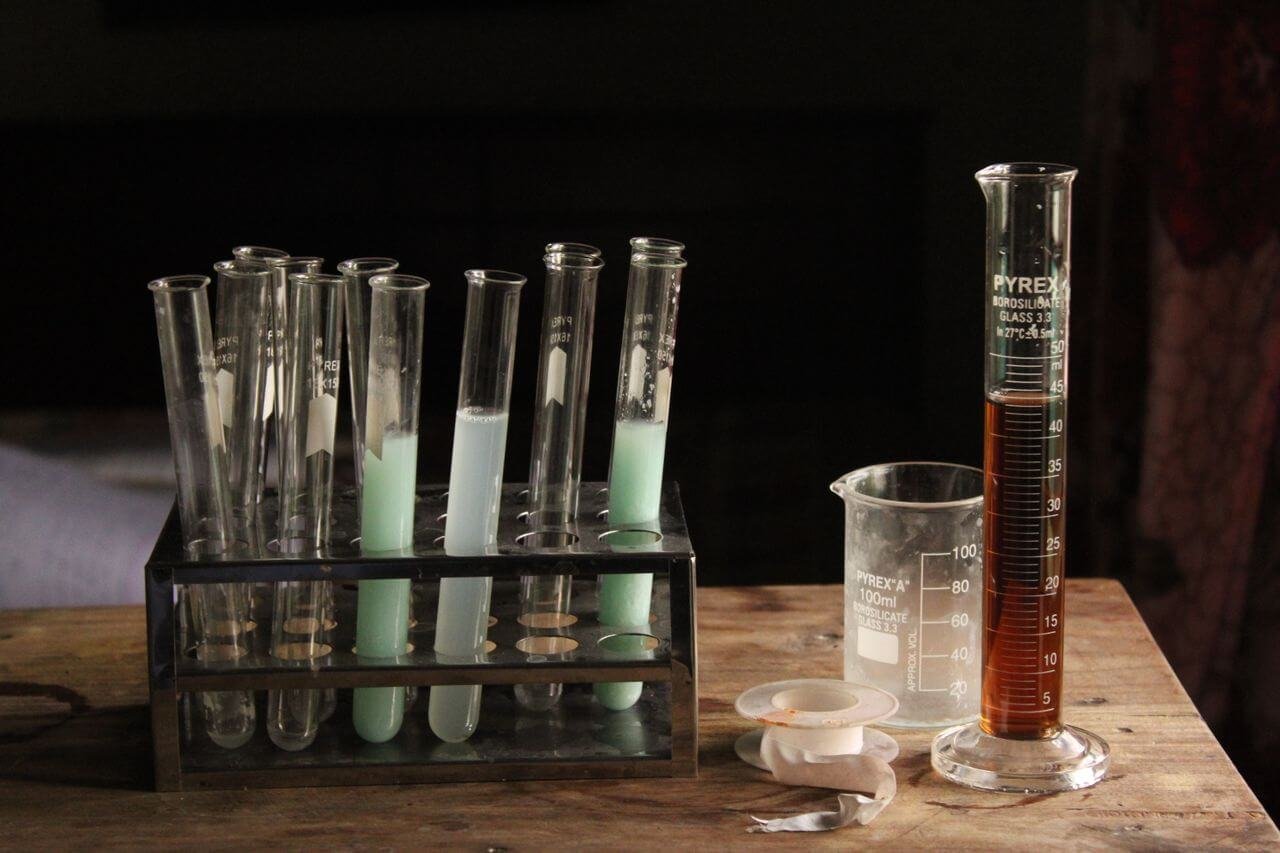 Glass test tubes and beakers with liquids on a wooden table, perfect for illustrating scientific experiments.