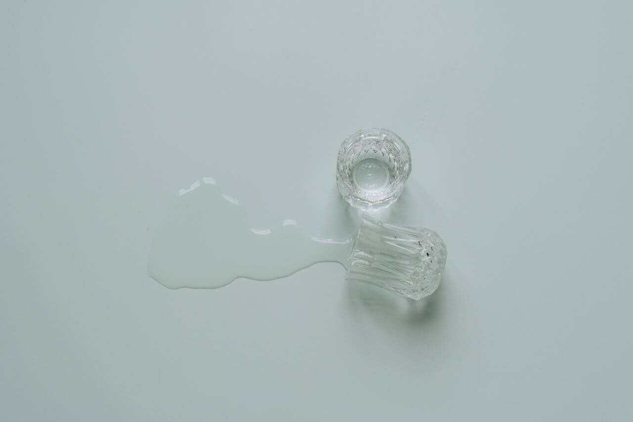 A clear glass tumbler spilled on a flat surface, creating a minimalist and serene scene.