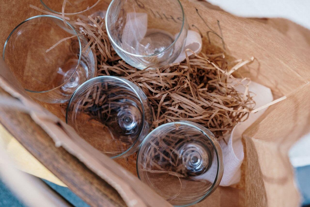 Four wine glasses nestled in straw packaging, viewed from above, ideal for gift or transport concepts.