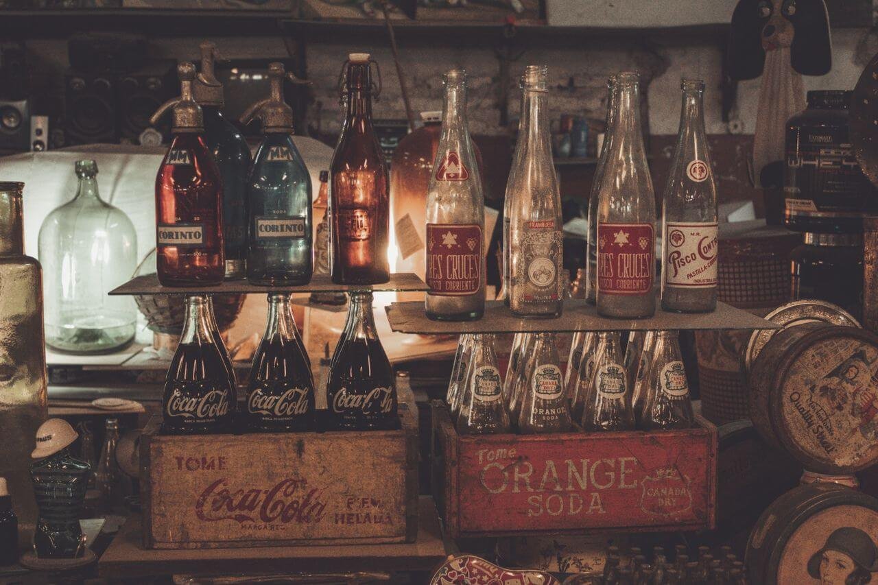 A nostalgic display of vintage soda bottles and crates with moody lighting.