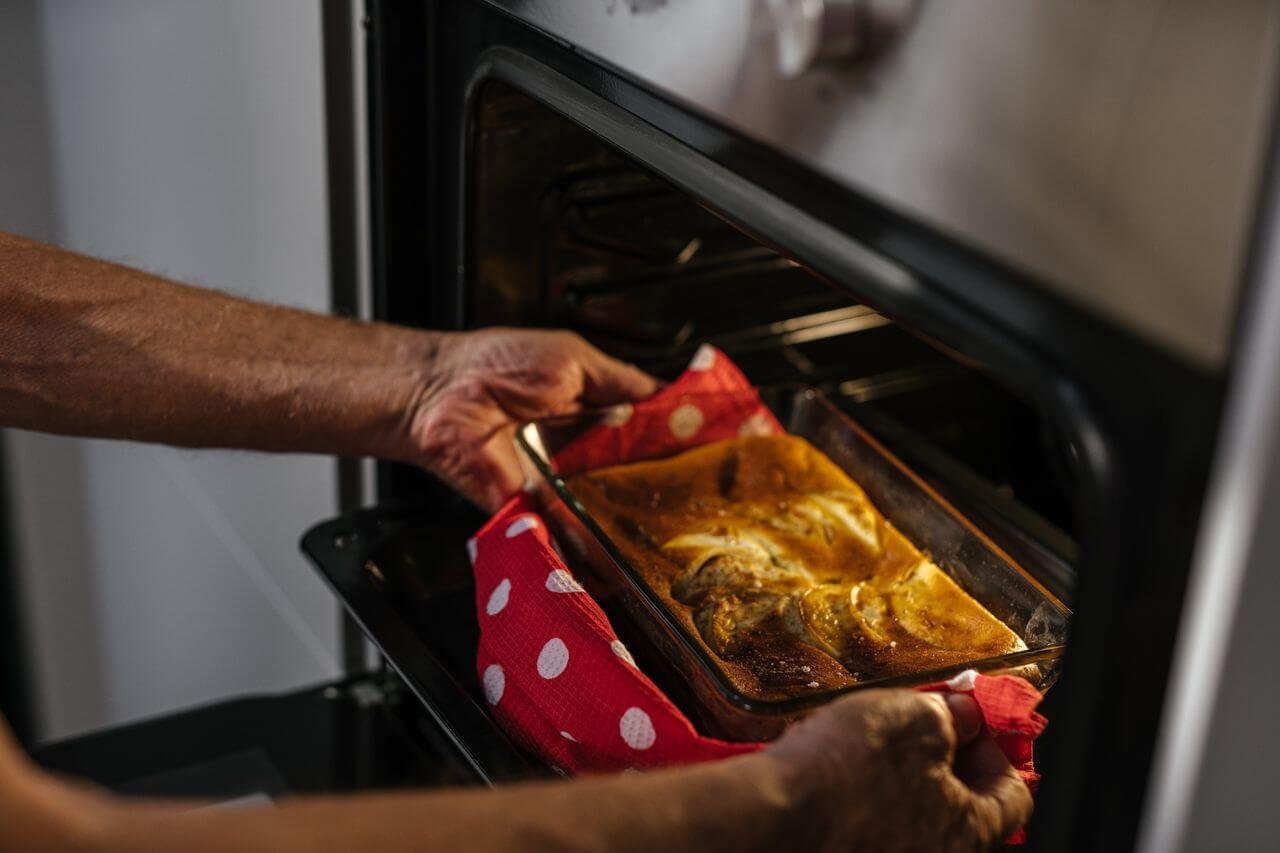 Person removes freshly baked cake from oven, showcasing home baking joy.